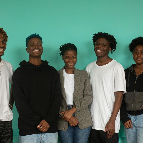 Diverse group of people smiling and stretching in a bright, modern studio.
