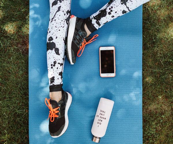 Neatly folded sportswear, a water bottle, and sneakers ready for a workout.