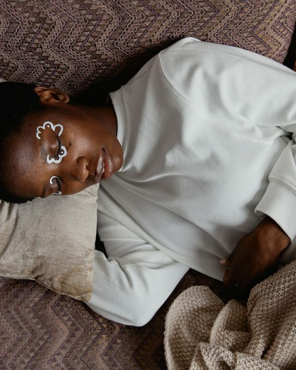 Person sitting peacefully with eyes closed in a calm, minimalist environment.